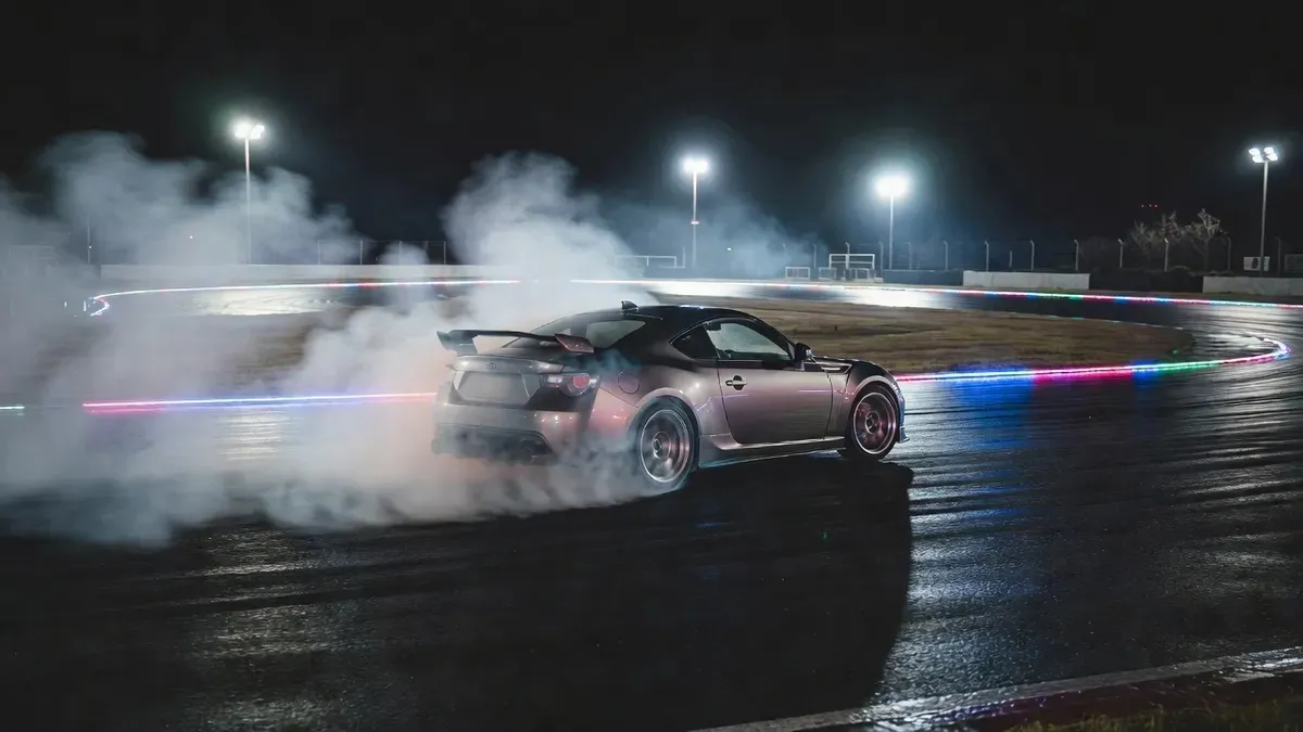 Nissan drift car cornering under floodlights at a closed circuit near Tokyo Japan — the kind of late-session runs you build to during a private drifting lessons Tokyo experience