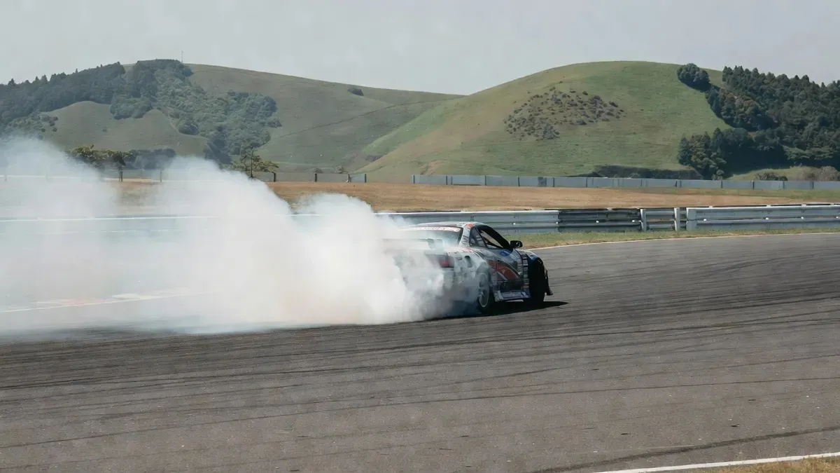 Nissan drift car sliding sideways through a corner at Minami Chiba Circuit during a private drifting lessons Tokyo session with OG instructors in Japan